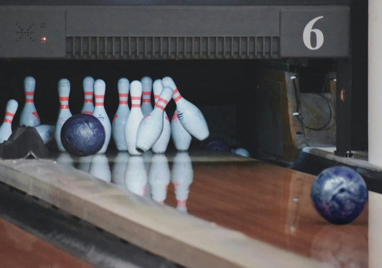Ten pins being knocked over by bowling ball